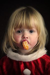 Dziewczynka z mandarynką w buzi